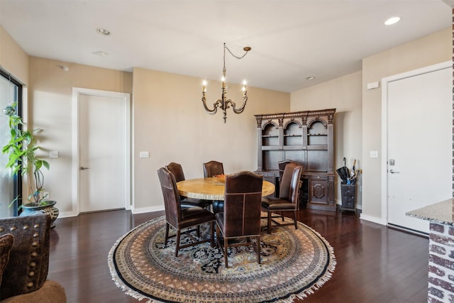 dining space with dark wood-type flooring and an inviting chandelier