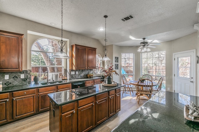 kitchen with a textured ceiling, a kitchen island, backsplash, and black appliances