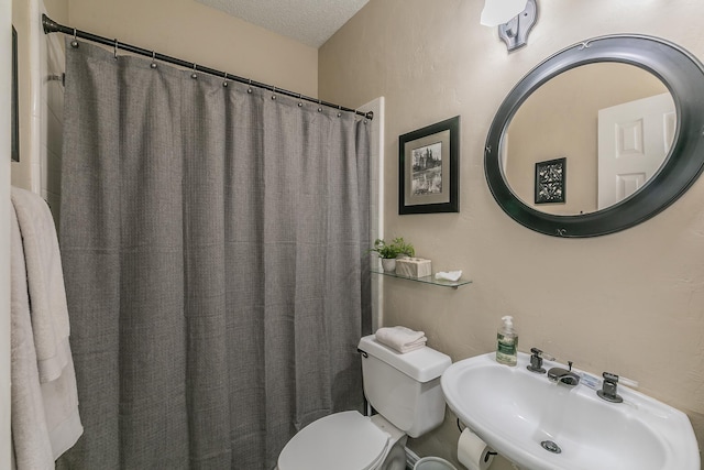 bathroom with toilet, sink, and a textured ceiling