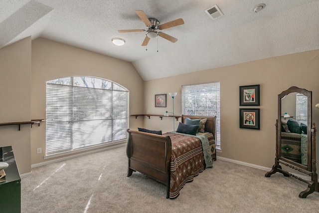 bedroom with ceiling fan, light colored carpet, vaulted ceiling, and a textured ceiling