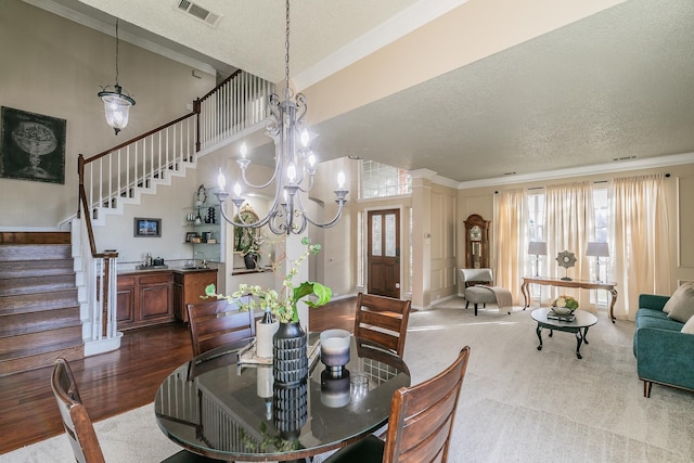 dining space with a textured ceiling, crown molding, and a chandelier