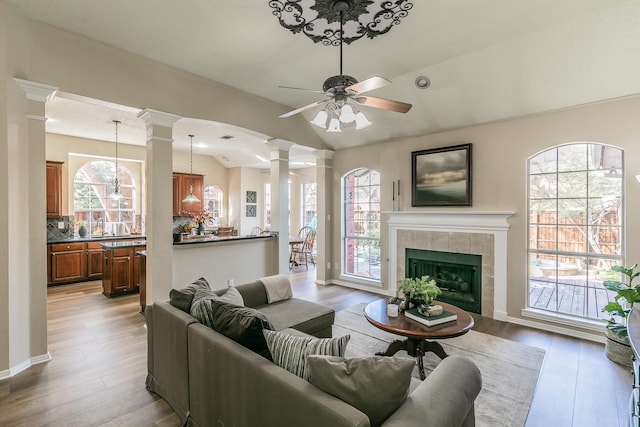 living room with vaulted ceiling, ceiling fan, light hardwood / wood-style floors, and a tiled fireplace