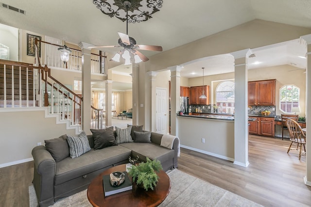 living room with ceiling fan, vaulted ceiling, decorative columns, and light hardwood / wood-style flooring