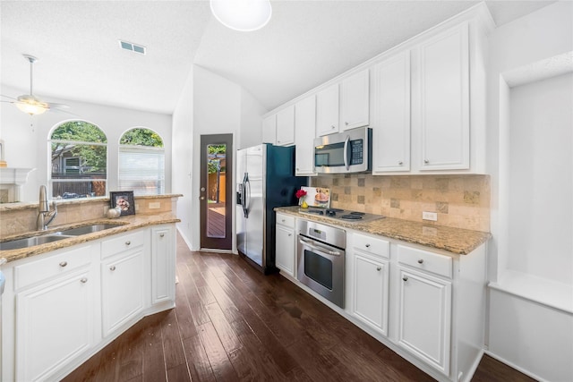 kitchen with stainless steel appliances, decorative backsplash, vaulted ceiling, white cabinets, and sink