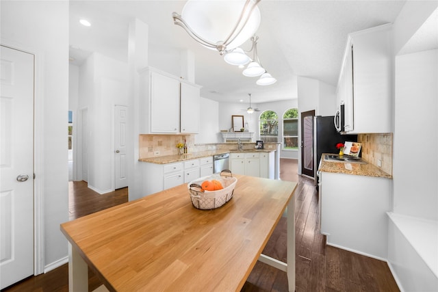 kitchen with appliances with stainless steel finishes, decorative backsplash, white cabinets, and decorative light fixtures