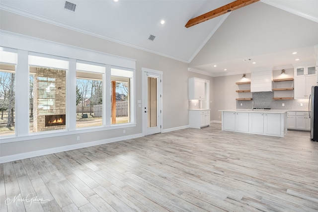 unfurnished living room featuring high vaulted ceiling, beamed ceiling, crown molding, and light hardwood / wood-style flooring