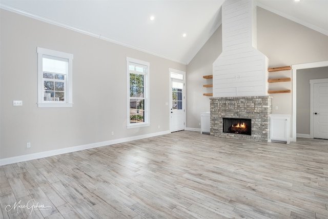 unfurnished living room featuring high vaulted ceiling, a stone fireplace, ornamental molding, and light hardwood / wood-style flooring