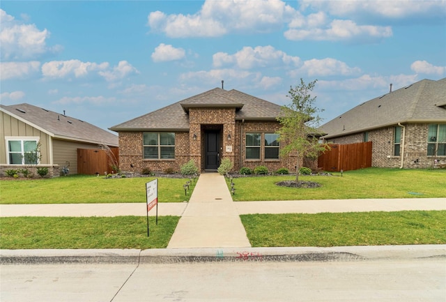 view of front facade featuring a front lawn, fence, and brick siding