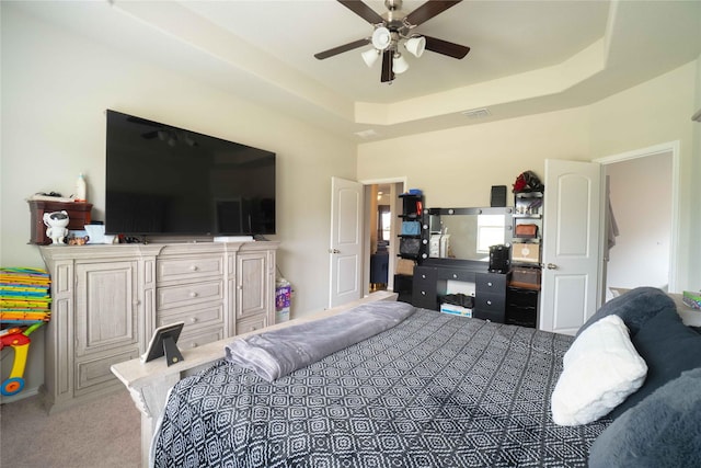 bedroom with a raised ceiling, carpet, visible vents, and ceiling fan