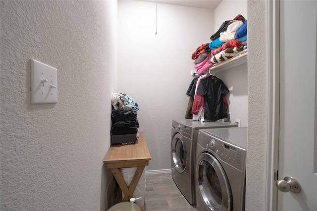 washroom featuring washer and clothes dryer, laundry area, a textured wall, and wood finished floors