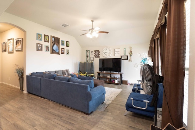 living room with arched walkways, visible vents, vaulted ceiling, and wood finished floors