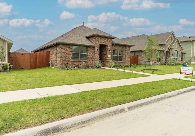 view of front of property with a front lawn, fence, and brick siding