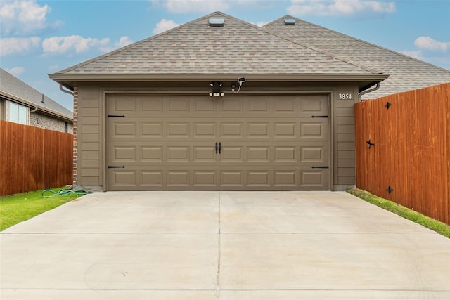 garage featuring driveway and fence