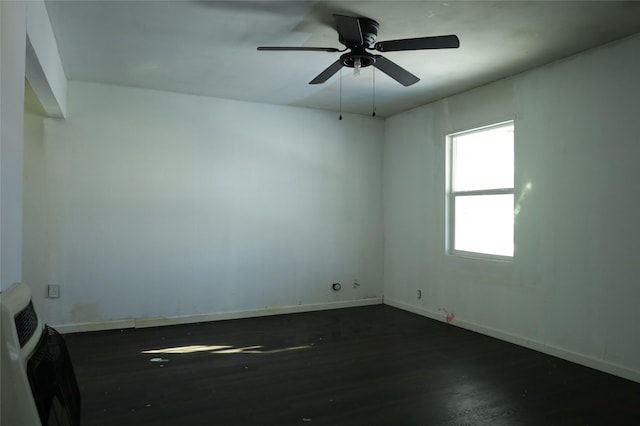 unfurnished room featuring ceiling fan, dark wood-type flooring, and heating unit