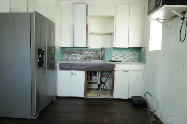 kitchen with white cabinets, decorative backsplash, stainless steel fridge, and sink