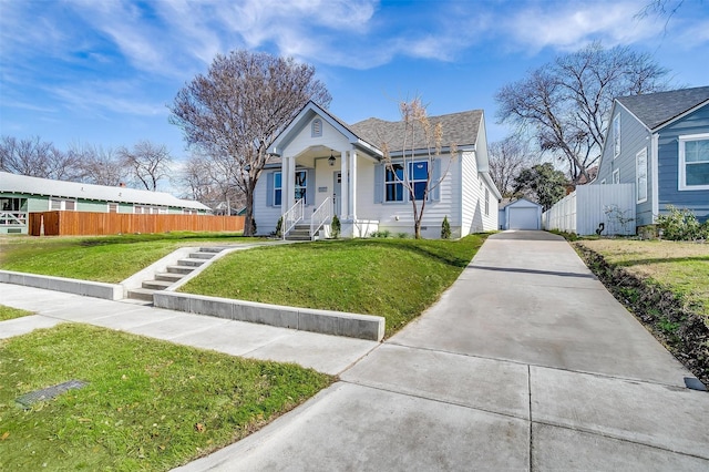 bungalow-style house with a garage, a front yard, and an outbuilding