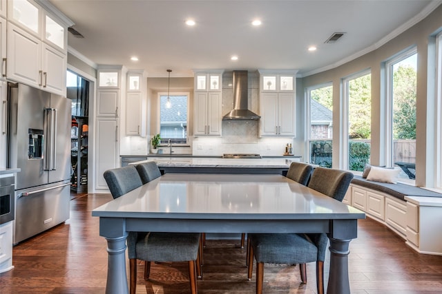 kitchen with white cabinets, wall chimney range hood, high end refrigerator, and pendant lighting