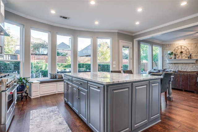 kitchen featuring gray cabinetry, dark hardwood / wood-style floors, high end range, a kitchen island, and crown molding