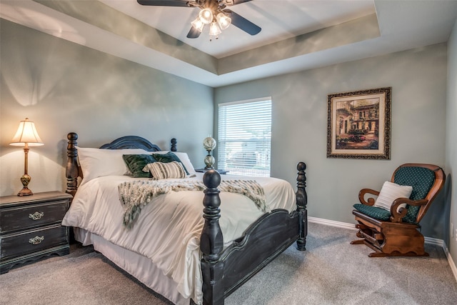 carpeted bedroom with ceiling fan and a raised ceiling