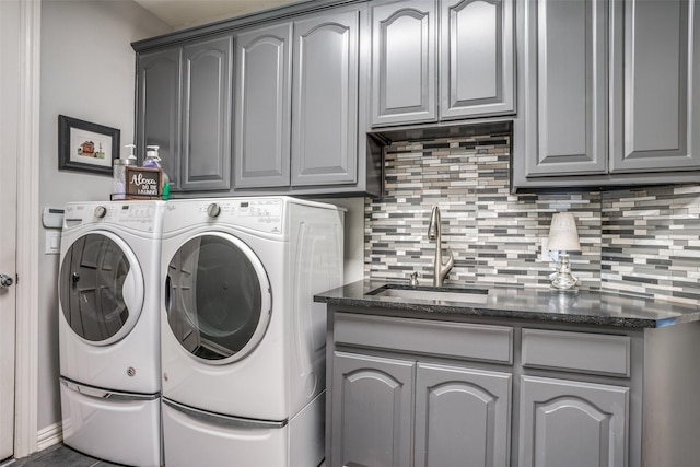 clothes washing area featuring sink, separate washer and dryer, and cabinets