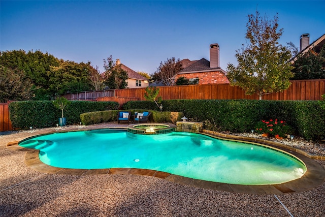 pool at dusk featuring an in ground hot tub