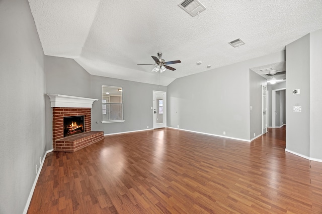 unfurnished living room with a brick fireplace, lofted ceiling, hardwood / wood-style floors, and ceiling fan