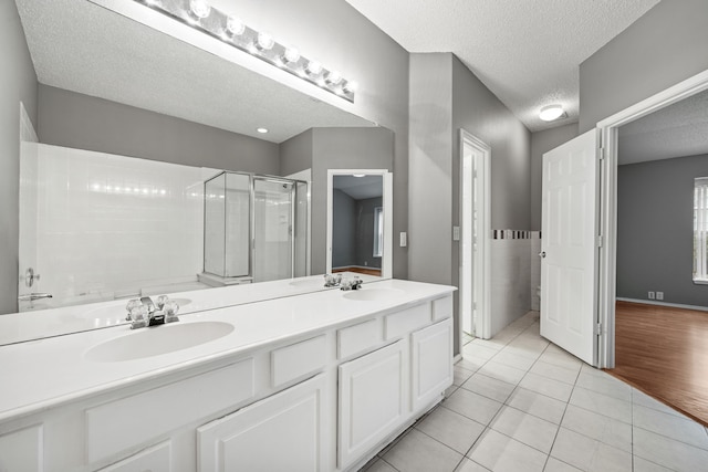 bathroom with a shower with shower door, a textured ceiling, tile patterned floors, and vanity