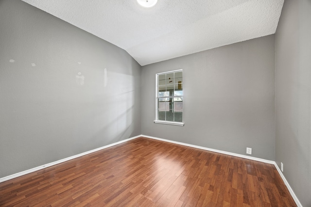 unfurnished room featuring lofted ceiling, a textured ceiling, and hardwood / wood-style flooring