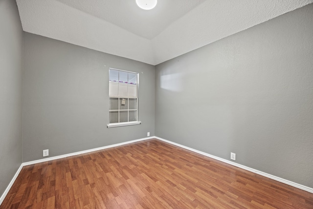 empty room featuring lofted ceiling and wood-type flooring