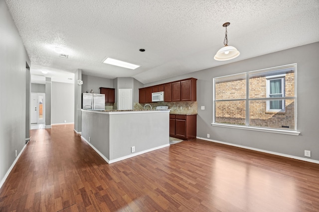 kitchen with stainless steel fridge, decorative backsplash, dark hardwood / wood-style floors, vaulted ceiling, and pendant lighting