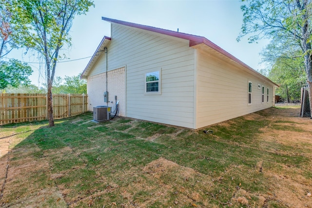 rear view of property featuring a lawn and central air condition unit