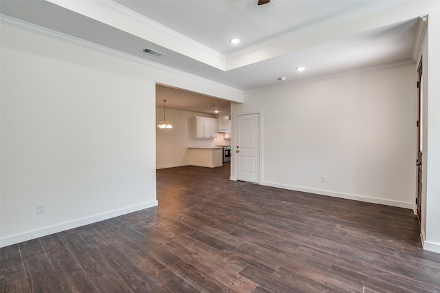 unfurnished living room with dark wood-type flooring, crown molding, a raised ceiling, and an inviting chandelier