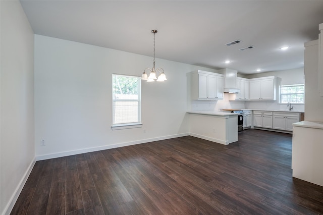 kitchen featuring stainless steel range with electric stovetop, kitchen peninsula, white cabinets, and decorative light fixtures