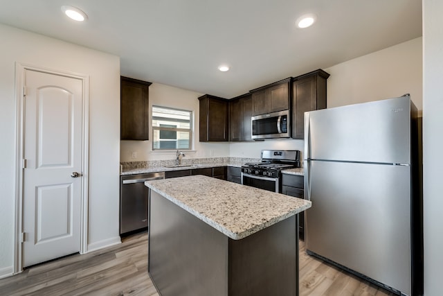 kitchen with light hardwood / wood-style floors, appliances with stainless steel finishes, dark brown cabinets, a kitchen island, and sink