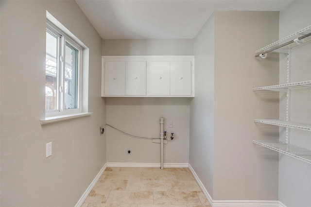 clothes washing area featuring electric dryer hookup and cabinets