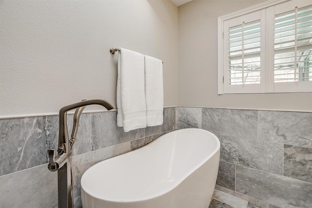 bathroom featuring a tub to relax in, tile walls, and sink