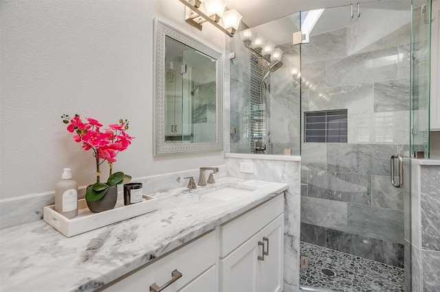 bathroom with a shower with shower door and vanity