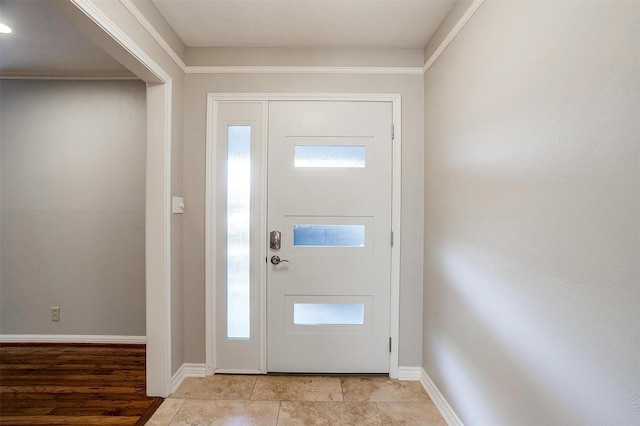 tiled entrance foyer featuring crown molding