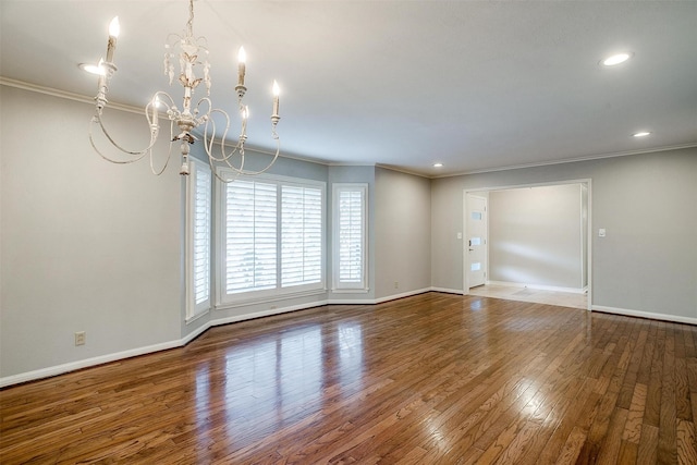 spare room featuring a notable chandelier, ornamental molding, and hardwood / wood-style flooring