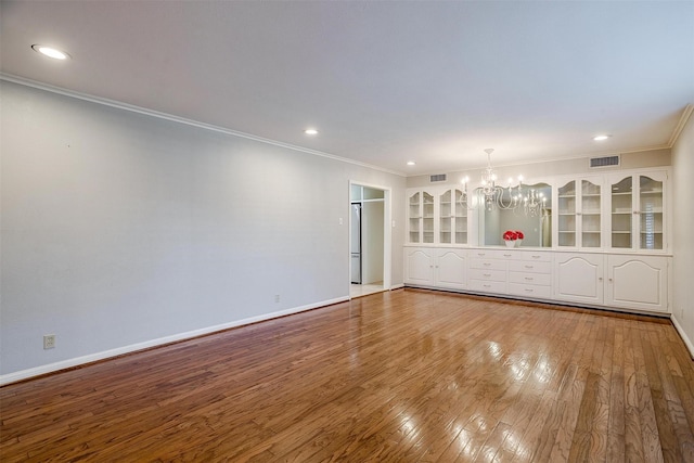 unfurnished room featuring wood-type flooring, crown molding, and a chandelier