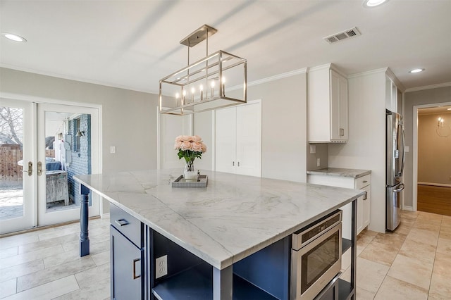 kitchen with light stone countertops, pendant lighting, appliances with stainless steel finishes, a kitchen island, and white cabinetry