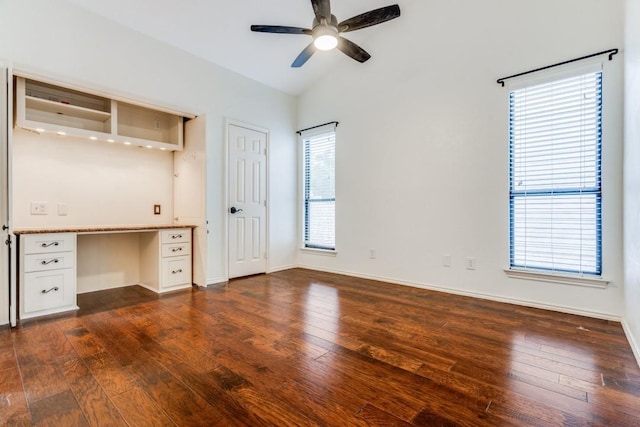 unfurnished bedroom featuring ceiling fan, dark hardwood / wood-style floors, lofted ceiling, built in desk, and multiple windows