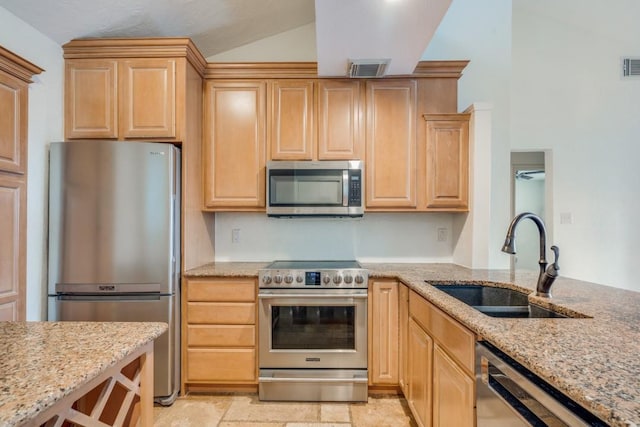 kitchen featuring ceiling fan, appliances with stainless steel finishes, light brown cabinetry, light stone counters, and sink