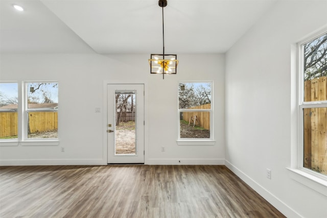 unfurnished dining area featuring a chandelier, a healthy amount of sunlight, and hardwood / wood-style flooring