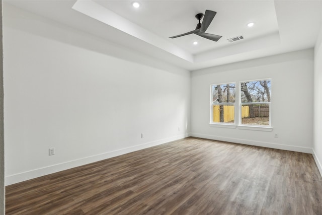 spare room featuring dark wood-type flooring, a tray ceiling, and ceiling fan