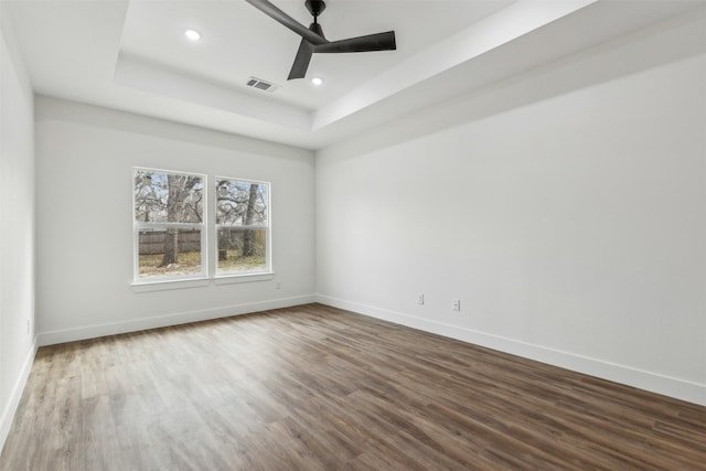 spare room with ceiling fan, a tray ceiling, and hardwood / wood-style floors