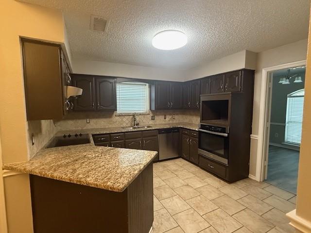 kitchen featuring kitchen peninsula, appliances with stainless steel finishes, sink, tasteful backsplash, and dark brown cabinetry