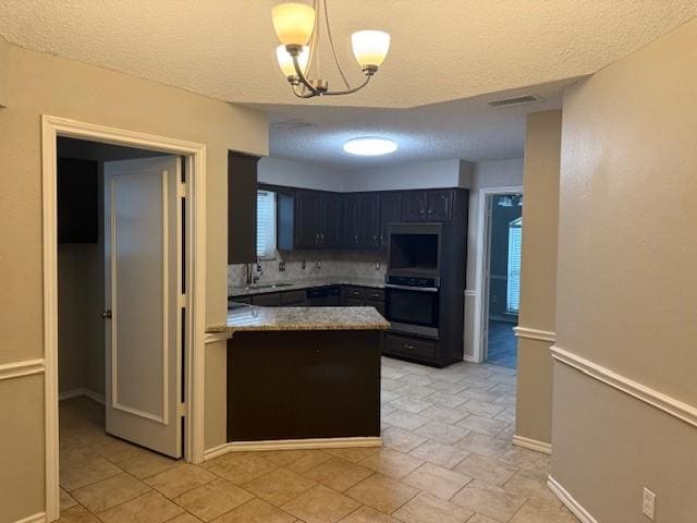 kitchen with a textured ceiling, sink, decorative backsplash, and a notable chandelier