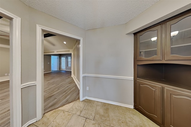 corridor with a textured ceiling and light tile patterned flooring