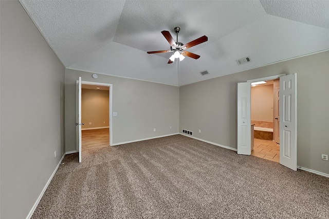 unfurnished bedroom featuring a textured ceiling, carpet, lofted ceiling, connected bathroom, and ceiling fan